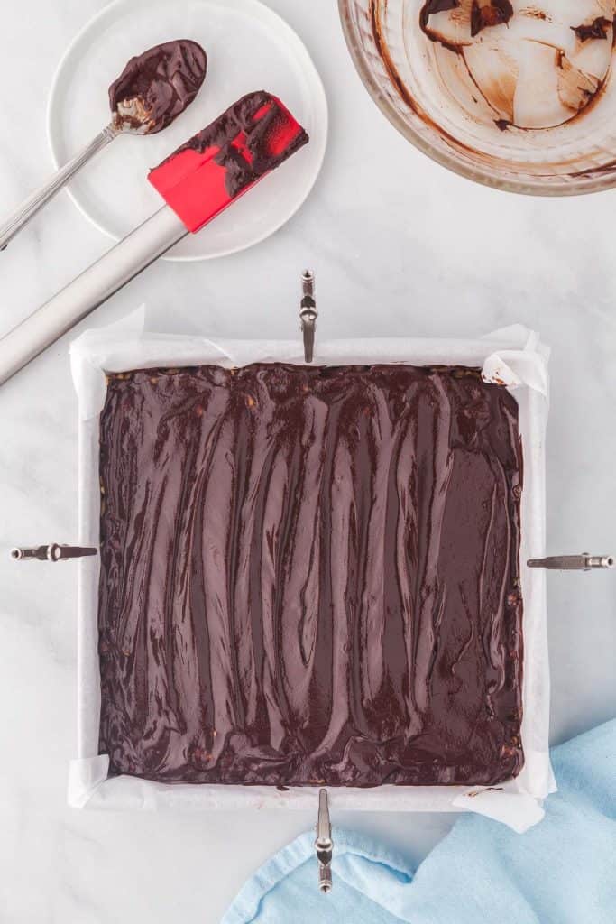 Overhead shot of an 8x8 pan filled with peanut butter rice krispie mixture and topped with a glossy coating of melted chocolate.