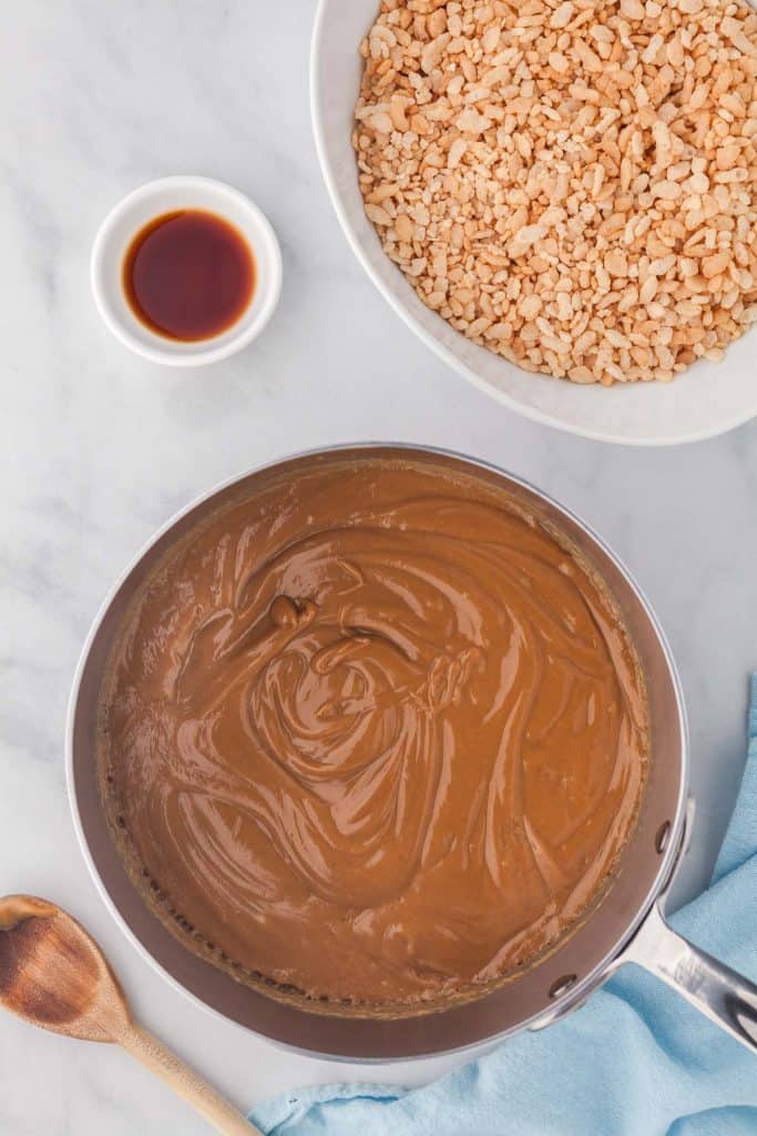An overhead shot of a small saucepan containing a thick brown mixture of peanut butter, maple syrup, and corn syrup.