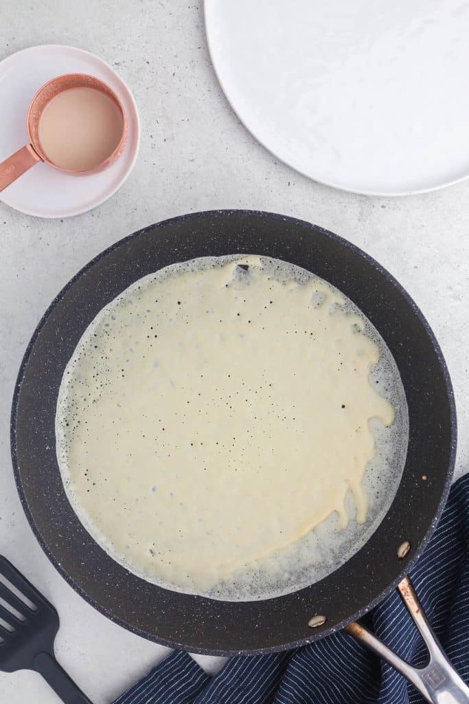Overhead shot of crepe batter in skillet after being swirled around the pan