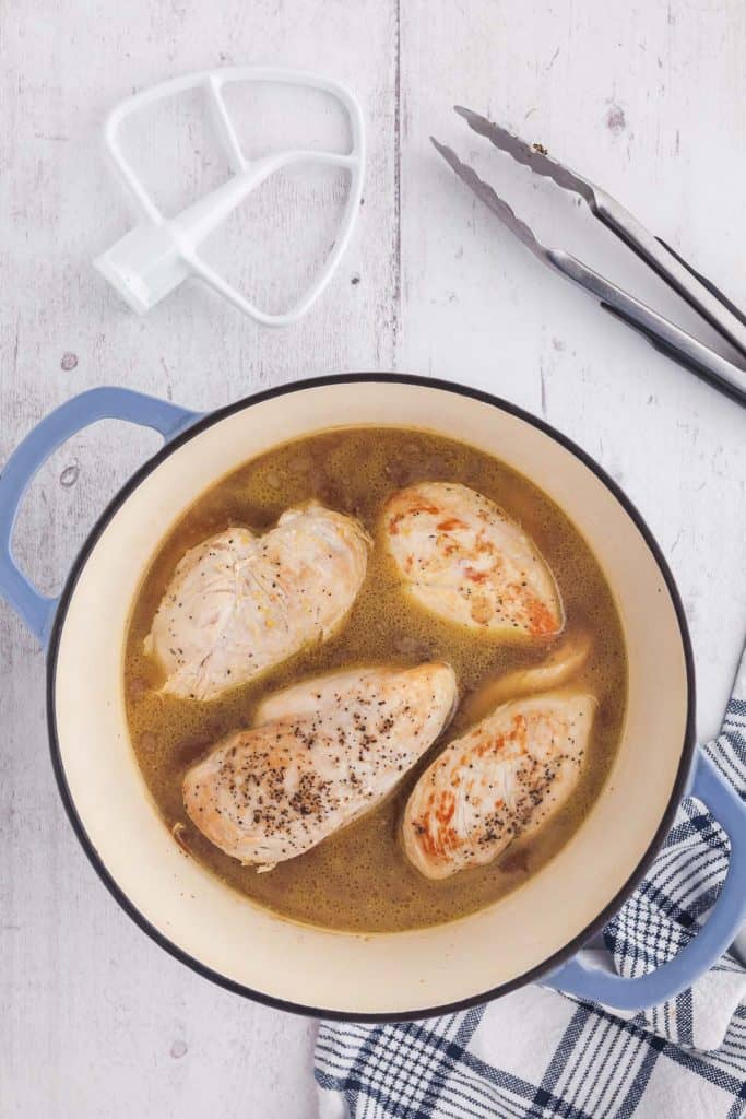 Overhead shot of chicken breasts in a dutch oven after having been seared and then poached in chicken broth.