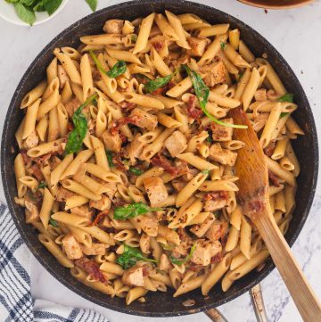 Overhead shot of a frypan filled with ready to serve Marry Me Chicken Pasta garnished with fresh basil.