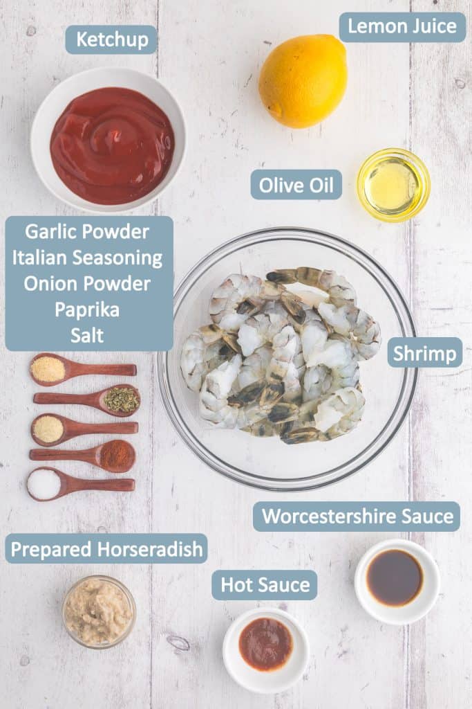 Overhead ingredient shot for Air Fryer Frozen Shrimp. Frozen Shrimp, ketchup, lemon, olive oil, garlic powder, Italian seasoning, onion powder, paprika, salt, Worcestershire sauce, hot sauce, horseradish