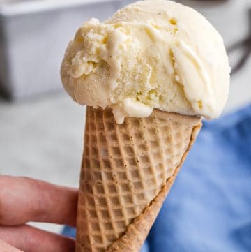Vanilla gelato ice cream cone, one scoop, being held up for a close up shot.
