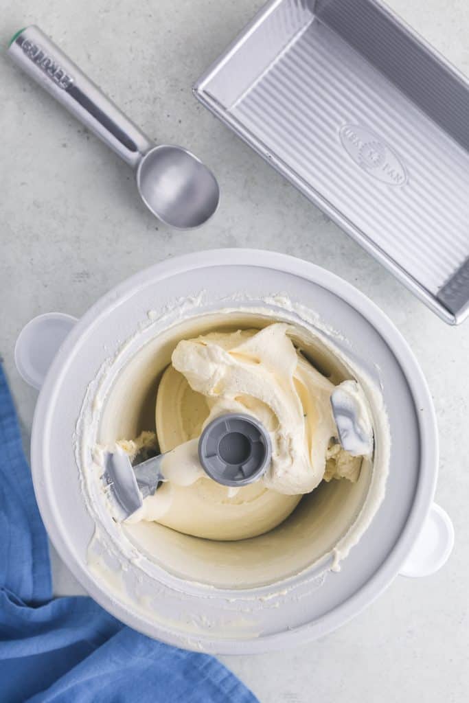Overhead shot of vanilla gelato after it has finished churning in an ice cream maker. It is a very pale yellow/white color with the consistency of soft serve.