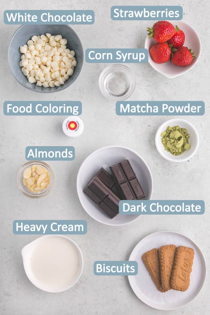 Overhead shot of ingredients necessary to make ganaches and decorations for dipping the mochi donuts in.  Ingredients include: white chocolate, dark chocolate, fresh strawberries, corn syrup, food coloring, slivered almonds, matcha powder, heavy cream, cookies