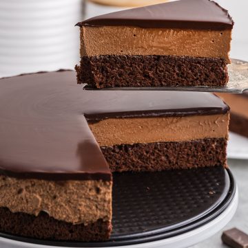 side angle shot of a piece of chocolate mousse cake being lifted out of the cake. You can easily see the three distinct chocolate layers