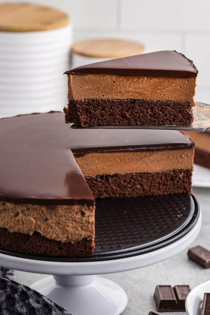 side angle shot of a piece of chocolate mousse cake being lifted out of the cake. You can easily see the three distinct chocolate layers