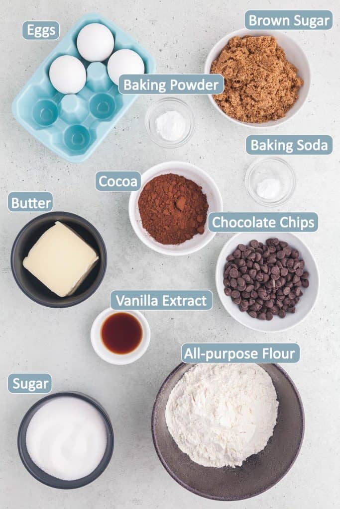 Overhead shot of the ingredients used in making this brookies recipe. Ingredients include: butter, brown sugar, white sugar, eggs, cocoa, baking powder, baking soda, chocolate chips, all-purpose flour, and vanilla extract