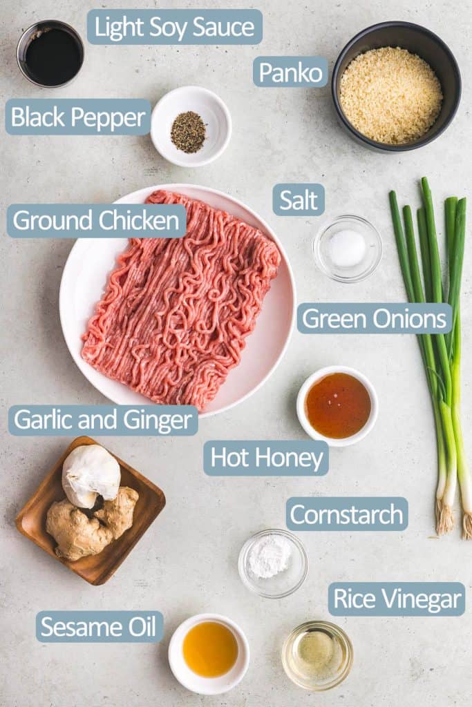 Overhead shot of all the ingredients needed to make air fry chicken meatballs.  Ingredients include, soy sauce, ground chicken, salt, black pepper, panko breadcrumbs, green onion, hot honey, garlic, ginger, cornstarch, sesame oil and rice vinegar.