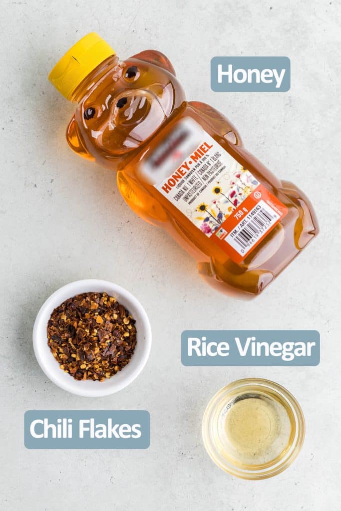 Overhead shot of the ingredients needed to make hot honey. Ingredients include: honey, dried chili flakes, and rice vinegar.