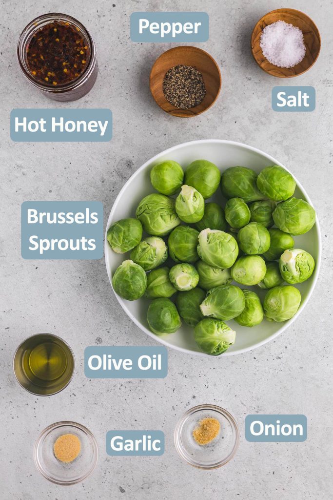 Overhead shot of the ingredients needed to make hot honey brussels sprouts. Ingredients include brussels sprouts, garlic powder, onion powder, olive oil, hot honey, black pepper and salt.
