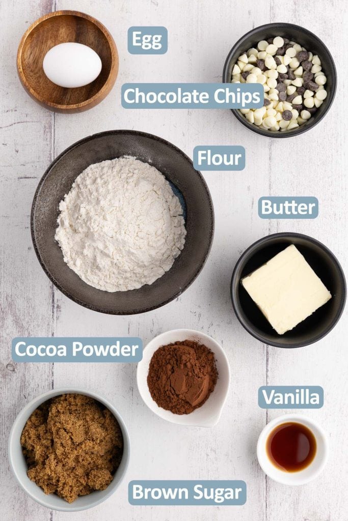 Overhead shot of all the ingredients necessary to make these chocolate chocolate chip cookie bars. Ingredients include: all-purpose flour, egg, chocolate chips, butter, cocoa, brown sugar, and vanilla extract.