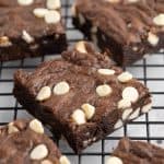 45 degree angle close up of the chocolate chocolate chip cookie bars cooling on a cooling rack. The camera is focused on the middle bar surrounded by a sea of cookie bars which are slightly out of focus.
