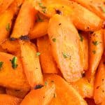 Close up overhead view of bright orange hot honey carrots. Just a little black charring on some edges from the roasting and garnished with fresh chopped parsley.