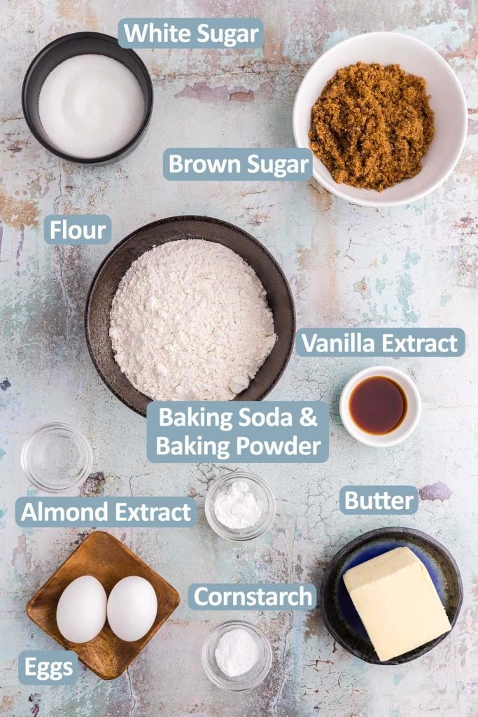 Overhead shot of the all the ingredients needed to make chocolate chipless cookies. Ingredients include: white sugar, brown sugar, flour, vanilla extract, almond extract, butter, egg, egg yolk, baking soda, baking powder, and cornstarch.