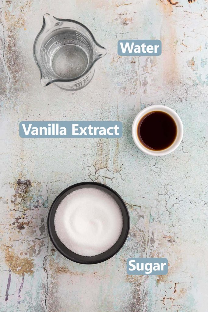 Overhead shot of the ingredients needed to make Vanilla Simple Syrup. Ingredients are: water, vanilla extract, and white sugar.