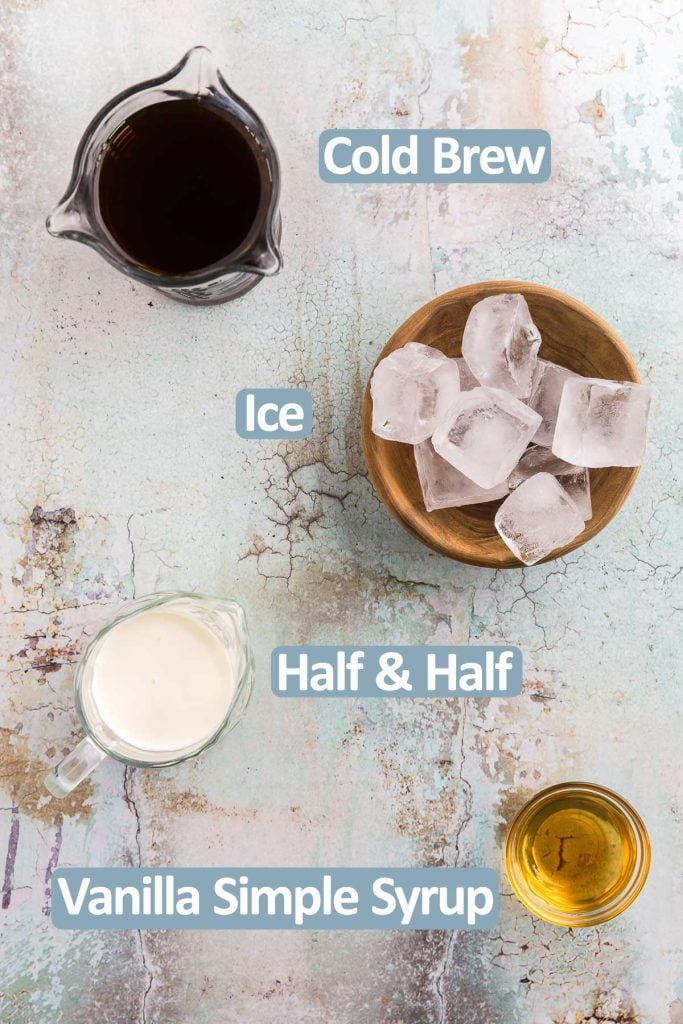 Overhead shot of the ingredients needed to make a vanilla sweet cream cold brew. Ingredients are: Cold brew, ice, half and half, vanilla simply syrup.