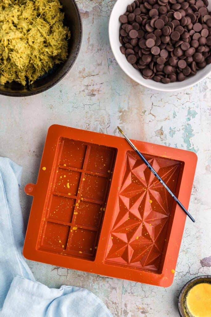 Overhead shot of a double chocolate mold which has been decorated with splashes of gold luster for the Dubai chocolate bar.