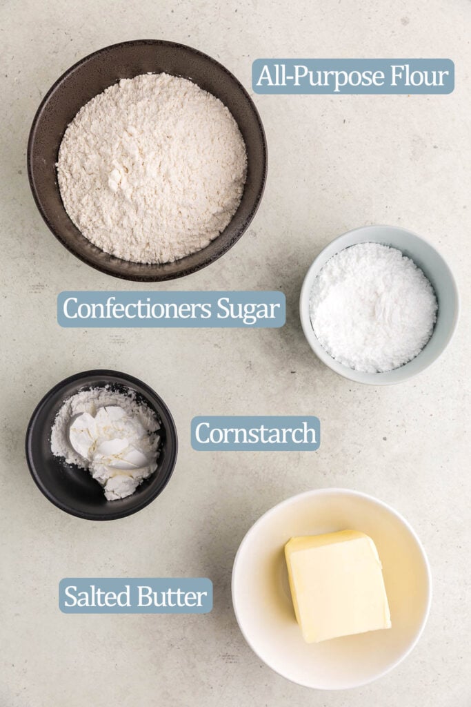 Overhead shot of the ingredients needed to make this easy shortbread recipe.  Ingredients are: all-purpose flour, confectioners sugar, cornstarch, and salted butter.