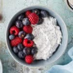 Overhead shot of a high protein Greek Yogurt bowl. Creamy Greek yogurt mixed with chia seeds and topped with fresh blueberries and raspberries.
