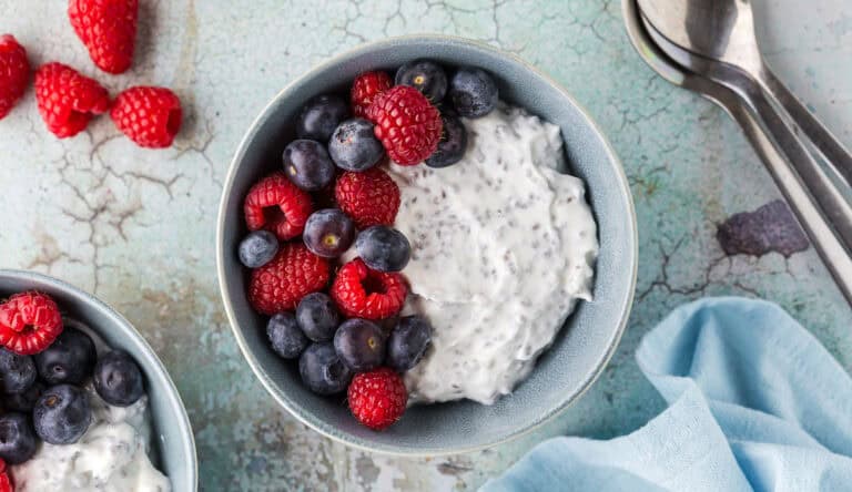 Overhead shot of a high protein Greek Yogurt bowl. Creamy Greek yogurt mixed with chia seeds and topped with fresh blueberries and raspberries.