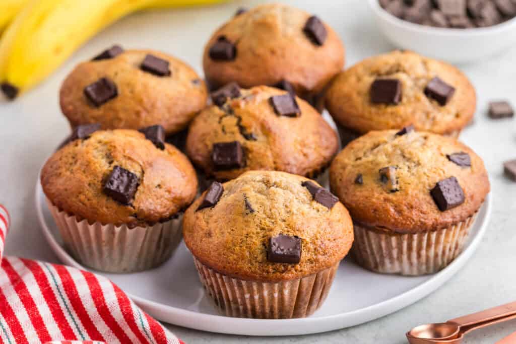 side shot of a serving plate filled with banana chocolate chunk muffins.