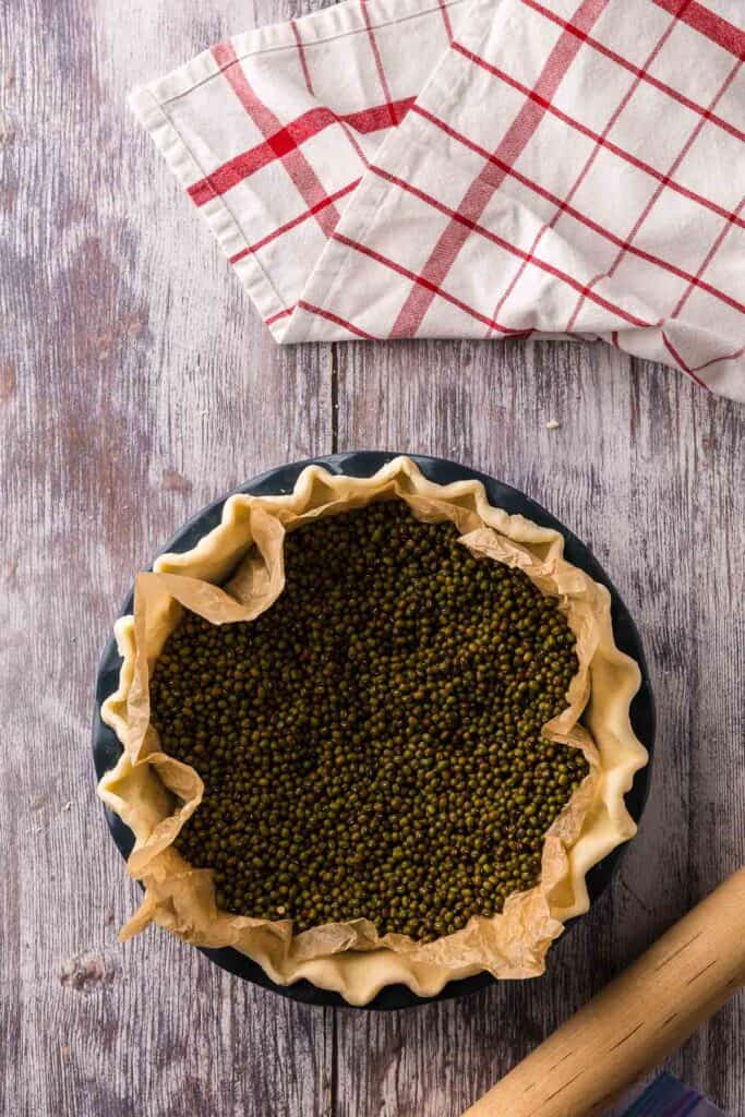 Pie crust filled with beans to prevent it from puffing up during blind baking.