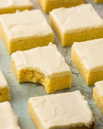 Horizontal shot of lemon cookie bars in neat and tidy rows. One of the middle bars has a bite taken out of it.