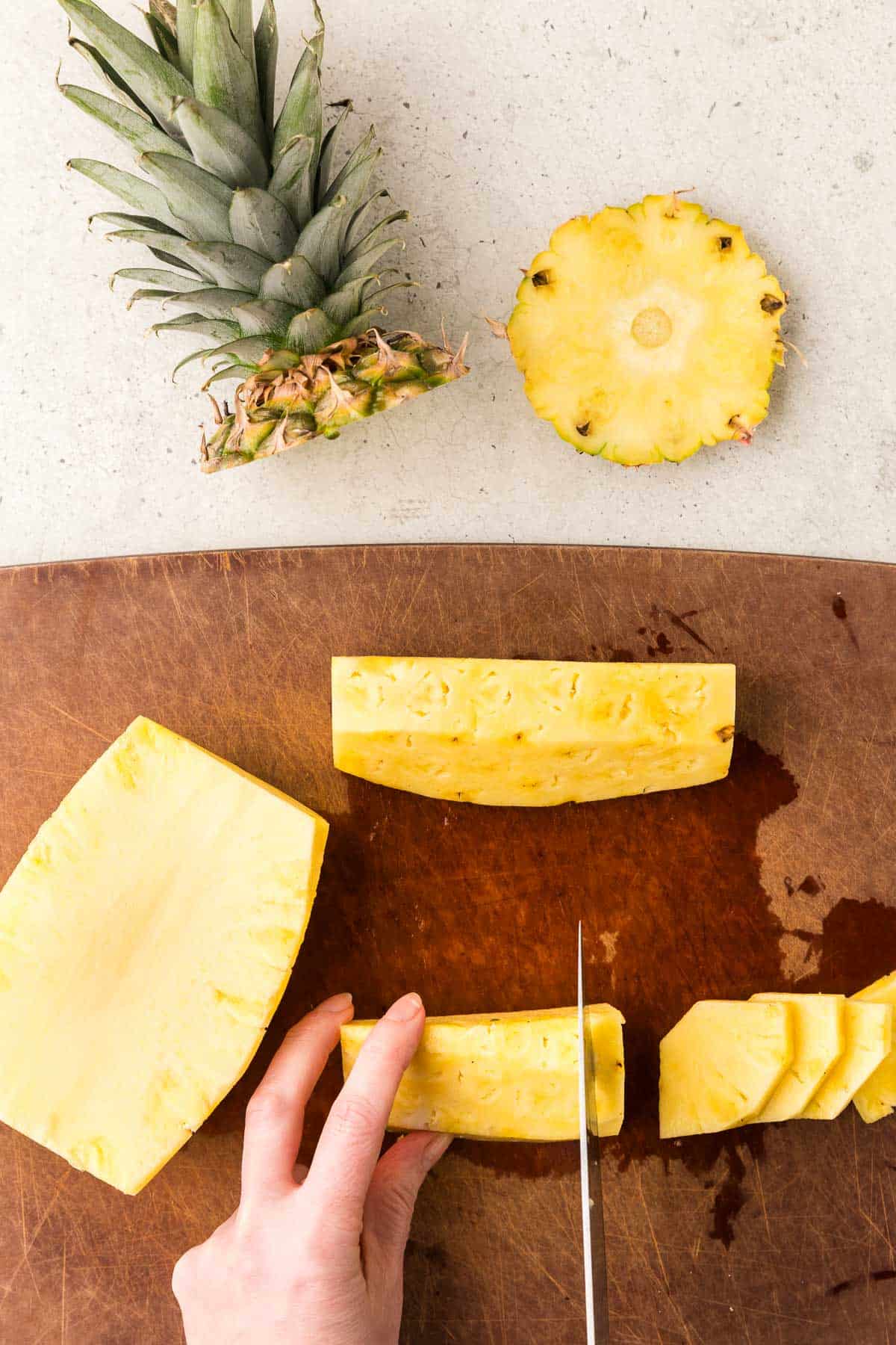 Pineapple on a cutting board after skin and core have been removed. Cutting into wedges for serving.
