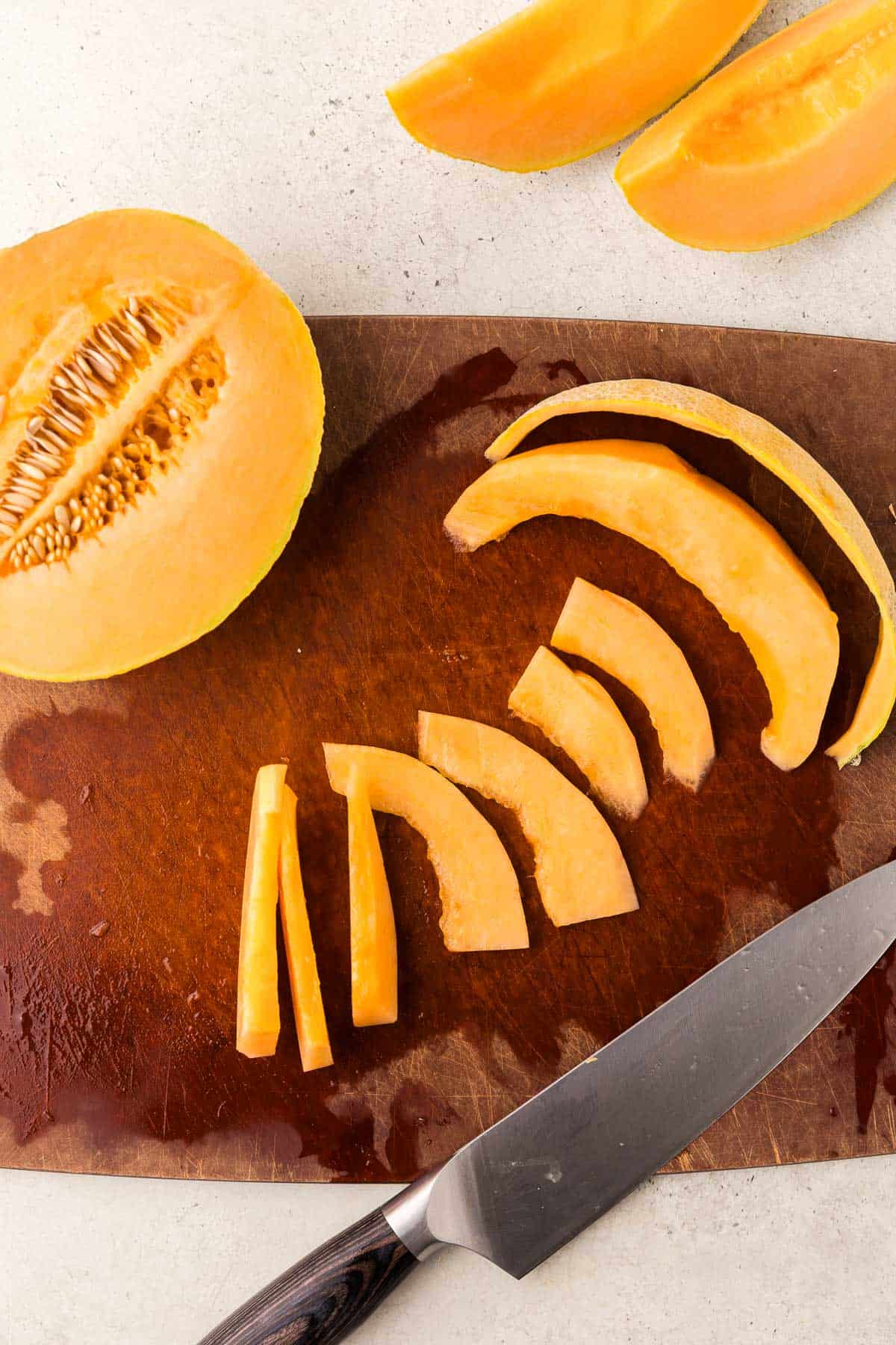 Overhead shot of a cantaloupe cut in half, seeds and skin removed then cut into slices.