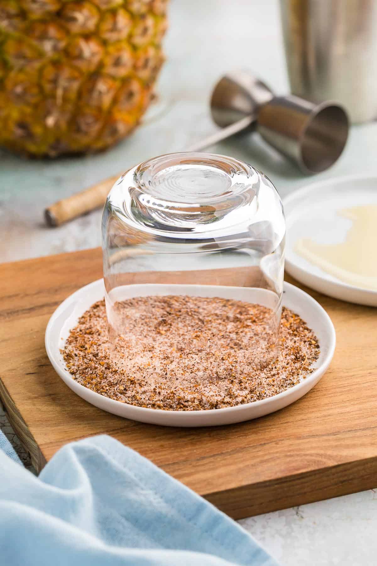 side shot of a lowball glass being rimmed with Tajin/sugar.