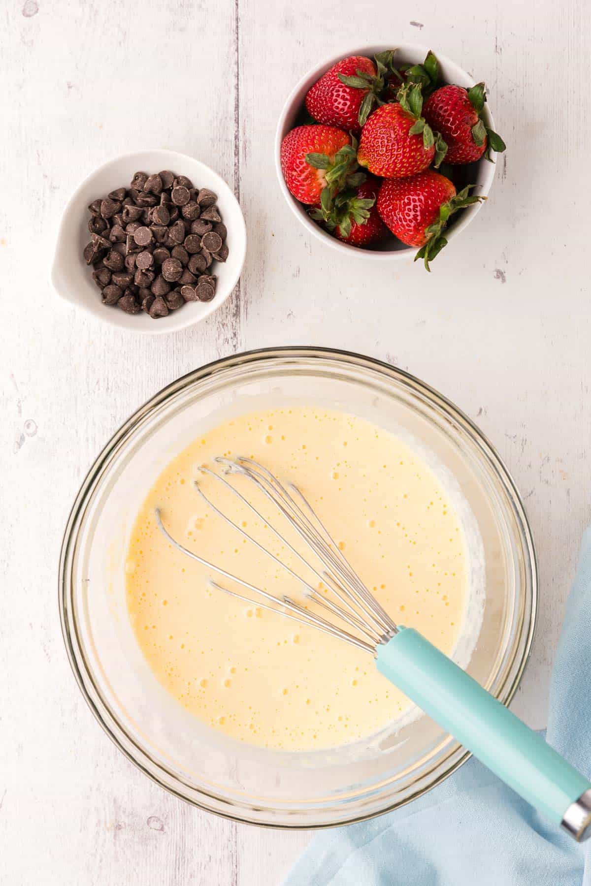 overhead shot of a glass mixing bowl with the wet ingredients combined. It's a light yellow/beige mixture.