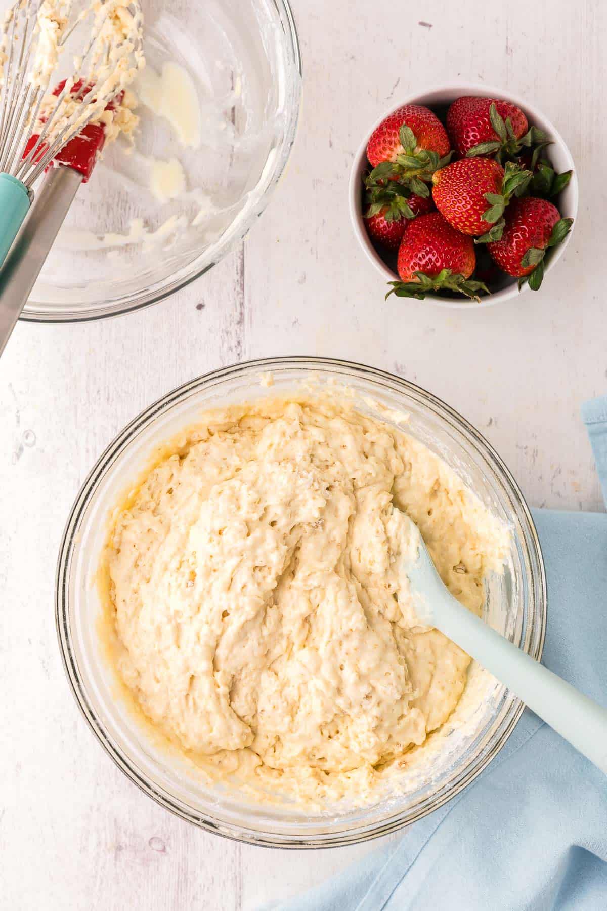 overhead shot of a large glass mixing bowl filled with the sheet pan pancake batter. It is thick and bubbly.