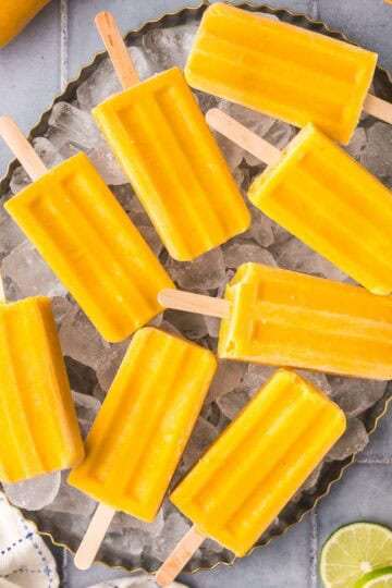 Overhead shot of mango popsicles laying on a plater of ice