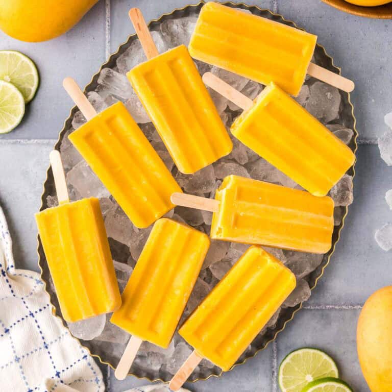 Overhead shot of mango popsicles laying on a plater of ice