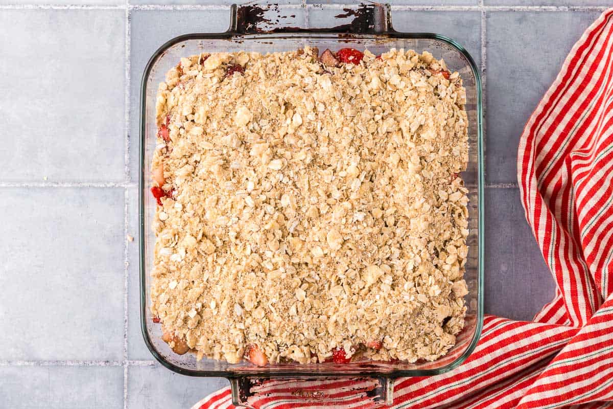 overhead shot of a square baking dish of strawberry rhubarb crisp with the crisp topping sprinkled on top before going in to the oven.