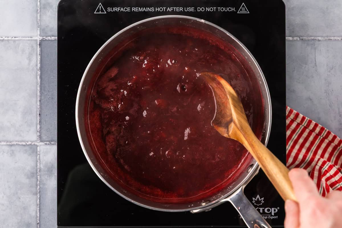 overhead shot of a saucepan filled with a jammy red liquid - strawberry rhubarb jam.