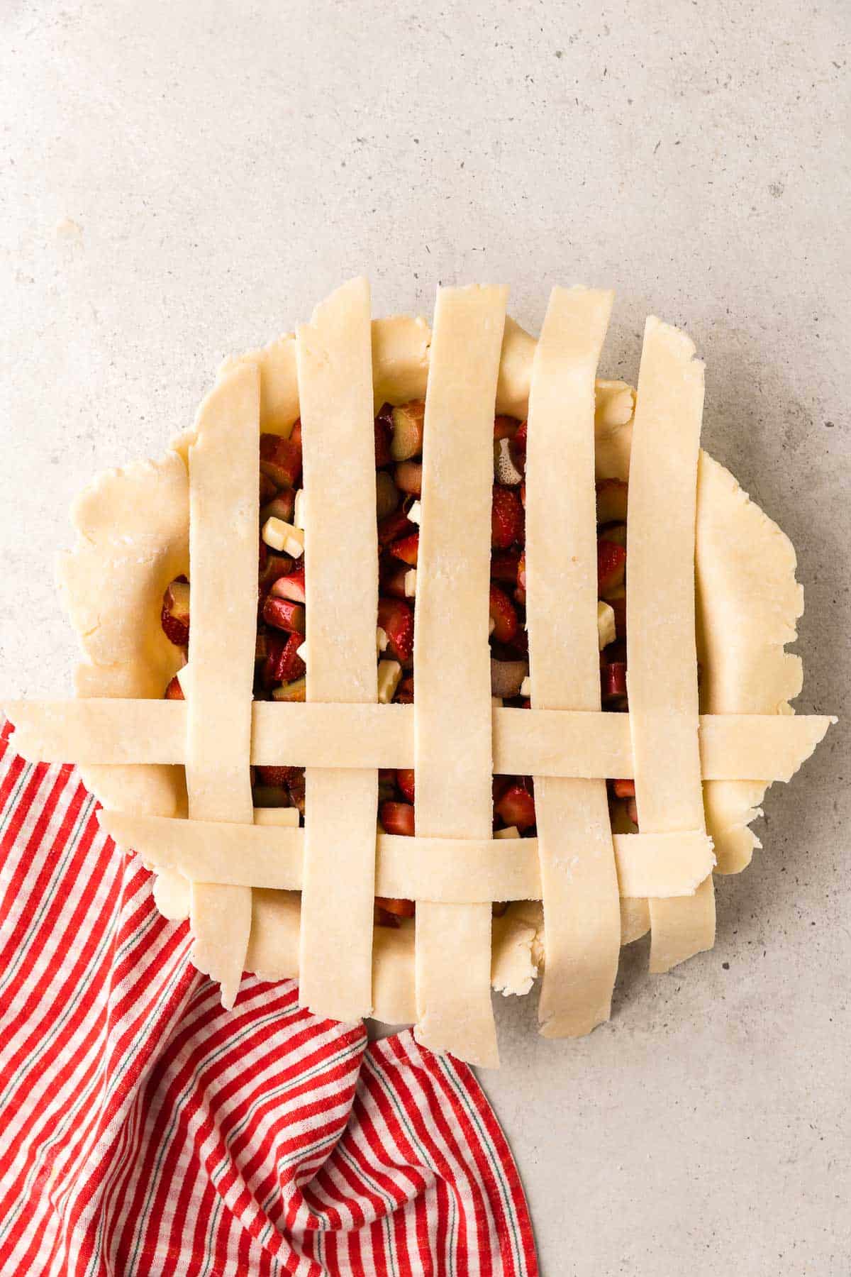overhead shot of the pie covered in 5 vertical dough strips and two horizontal strips. almost done making the the lattice top.