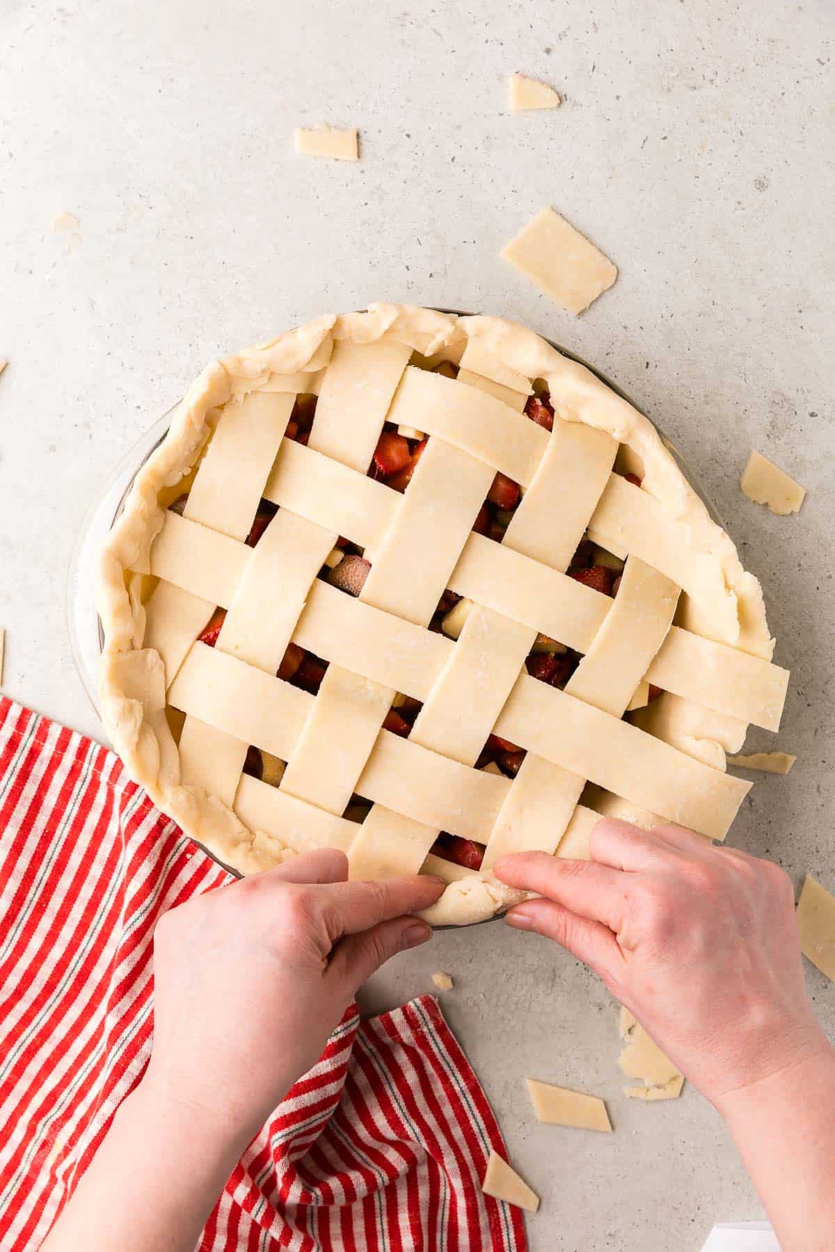 overhead shot of the pie now having the overhanging dough folded in and crimping together the bottom and top dough.
