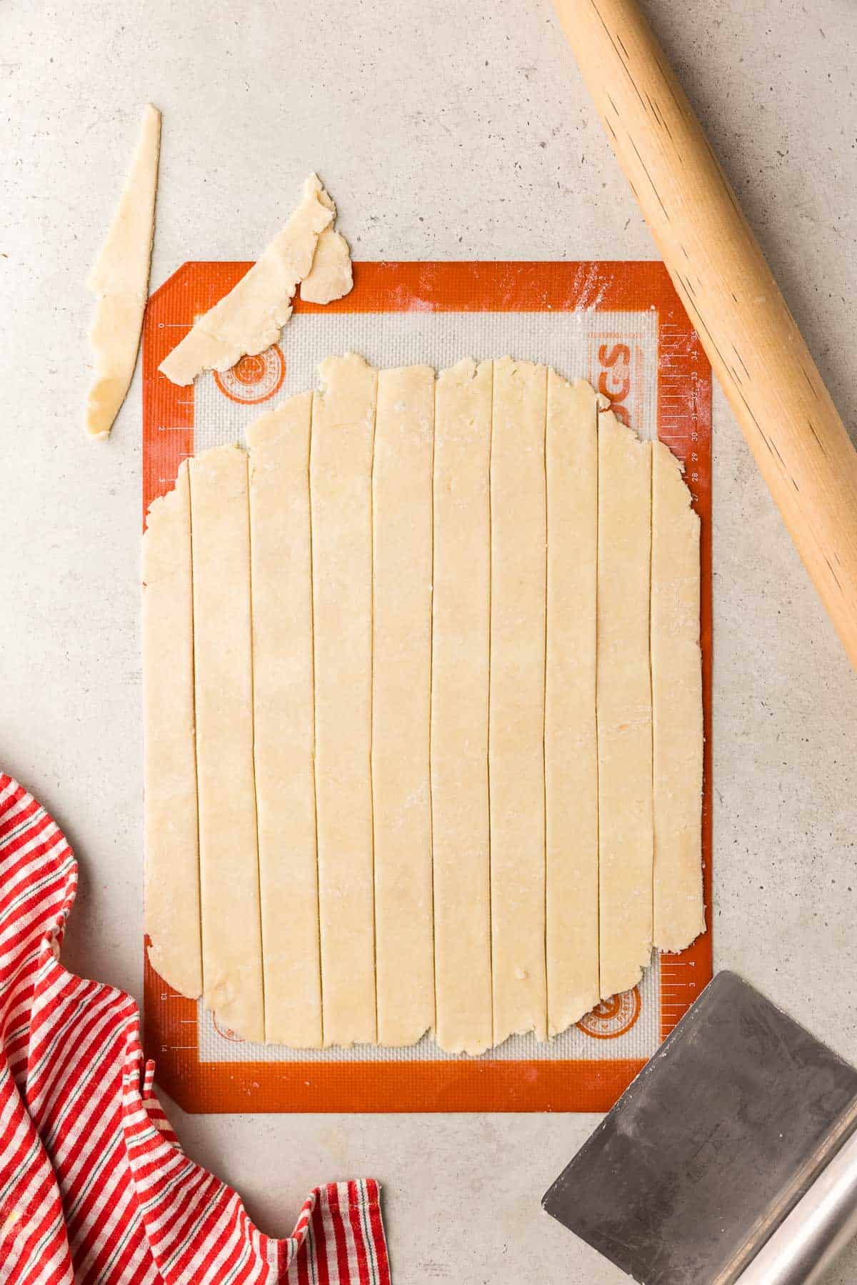 overhead shot of a pie crust dough rolled out and sliced into 1" strips to be used for the lattice top.