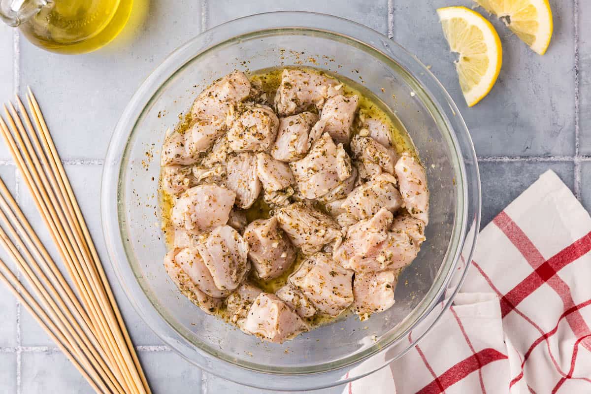 overhead shot of a glass bowl filled with chicken marinating in the souvlaki marinade.