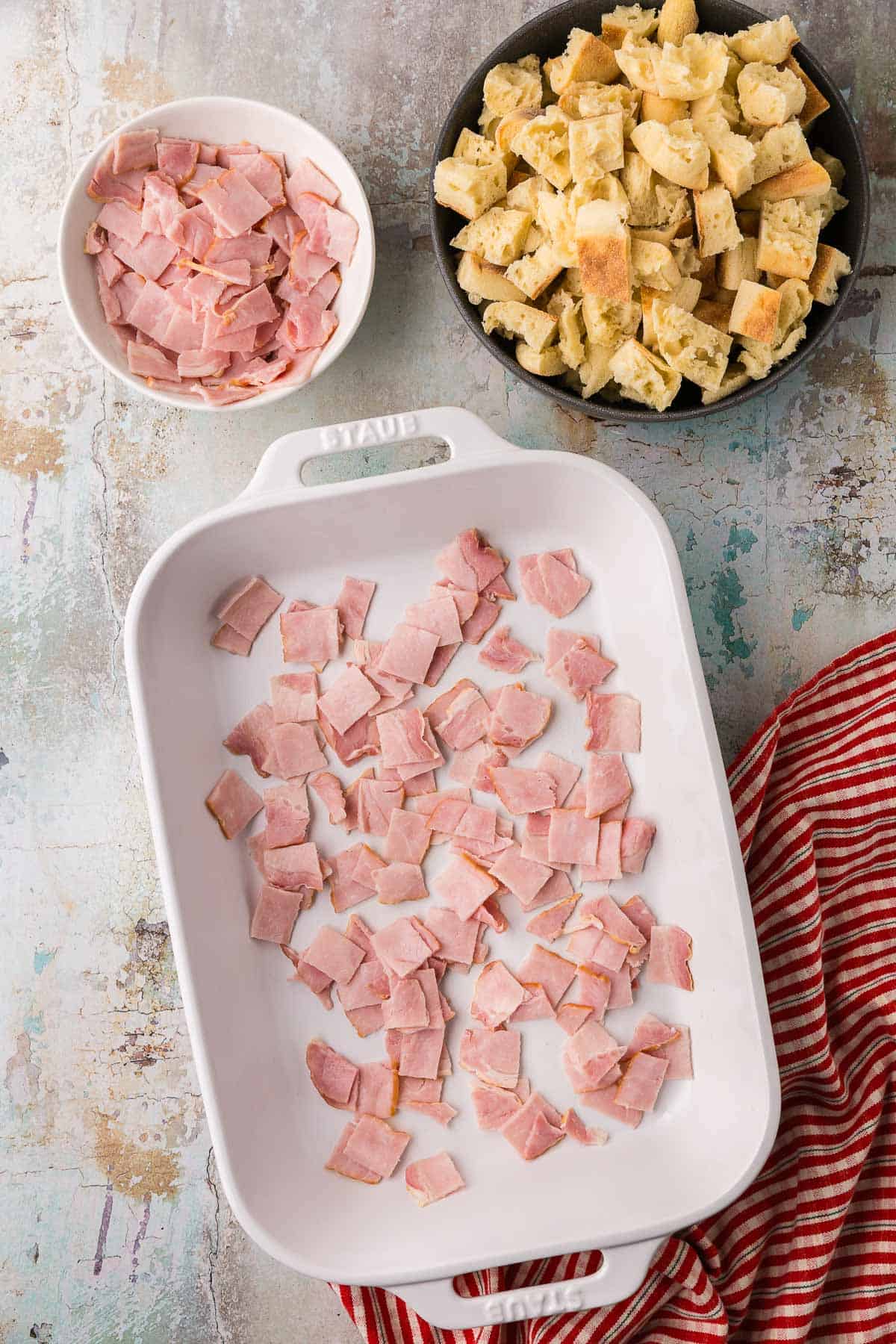 A white 9x13 casserole dish greased with butter and has a layer of back bacon added.