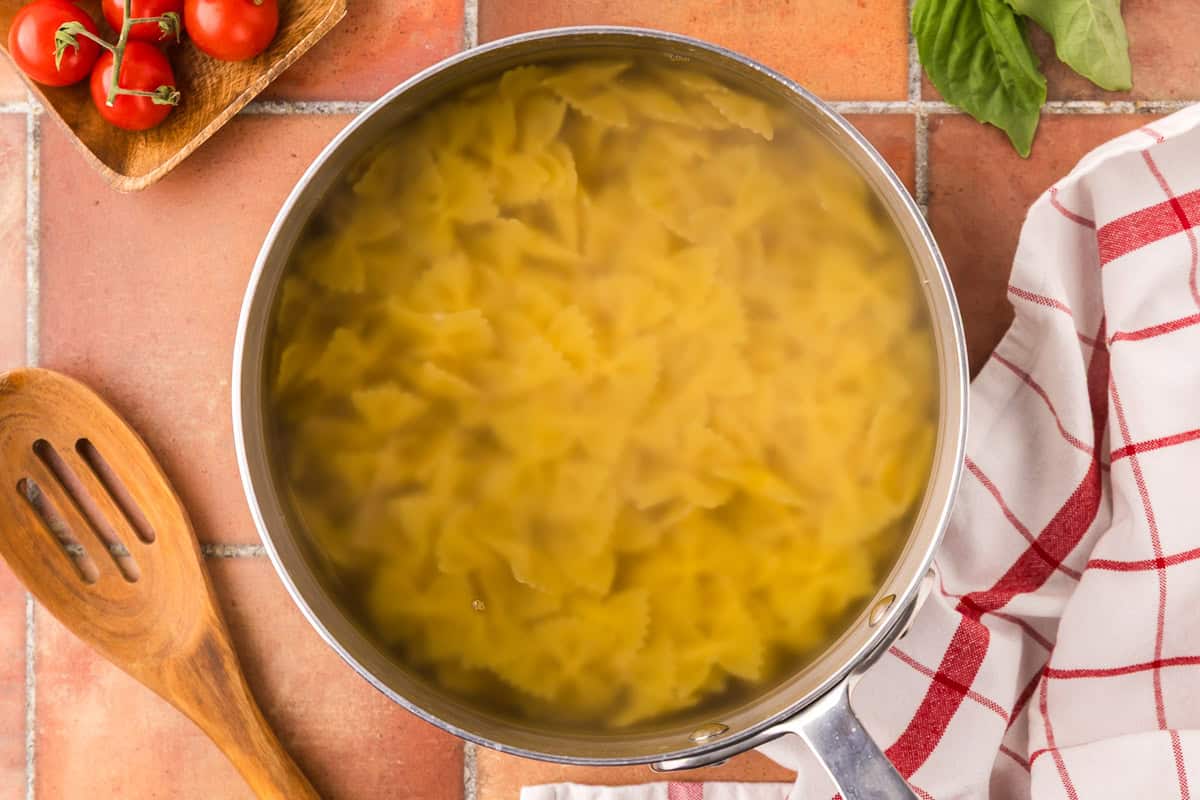 Overhead shot looking into a large saucepan filled with boiling water and bow tie pasta.