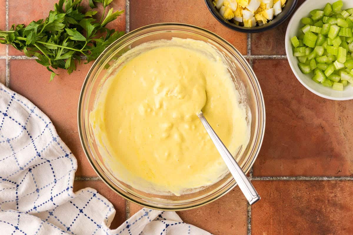 Overhead shot of the creamy yellow dressing after it has all been mixed together in the glass bowl.