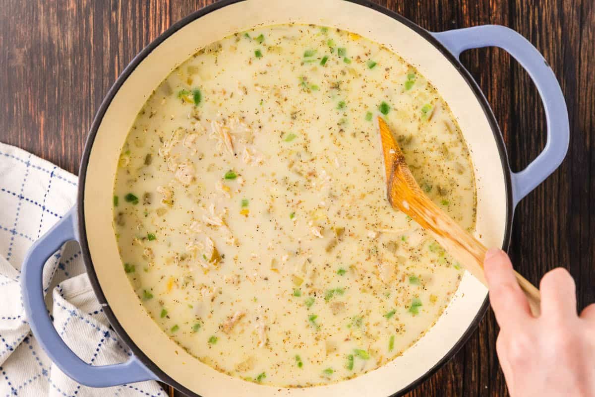 Overhead shot looking into a Dutch oven once all the ingredients for white chili chicken have been added. It is a creamy and chunky mixture.